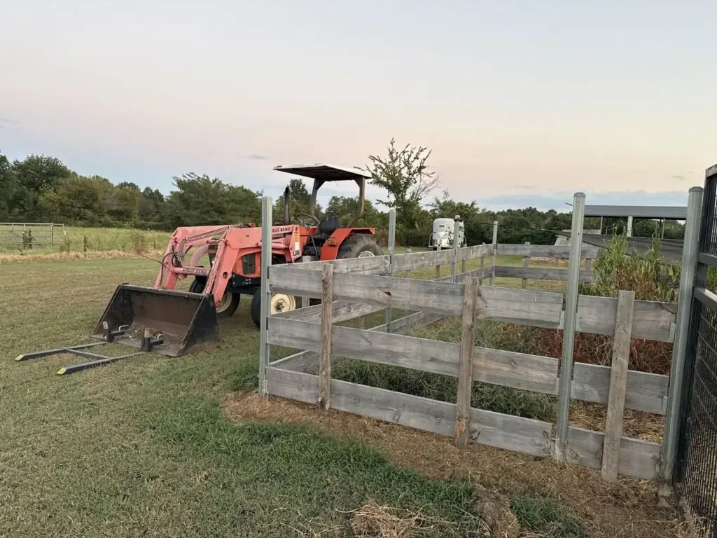 Red tractor beside the wooden rail pen at dusk on Porter & Prairie Family Farm